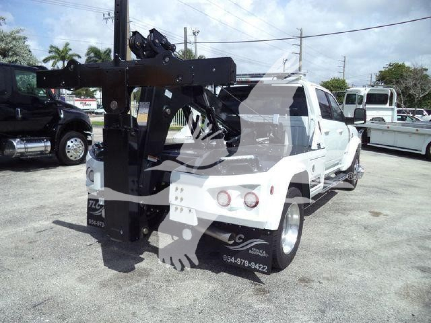 Tow truck with crane/winch mounting on back of white Ram 5500, winch apparatus visible, license plate area blocked by watermark, some text on side panels and bumper but not legible.