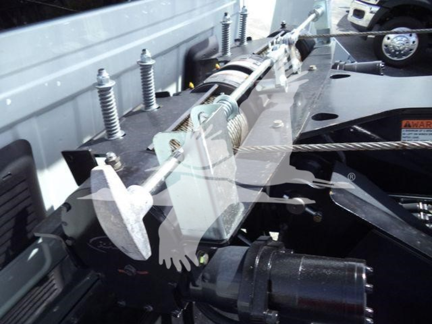 Truck winch system with steel cable and hydraulic winch mount in bed, showing control levers and mounting hardware.
