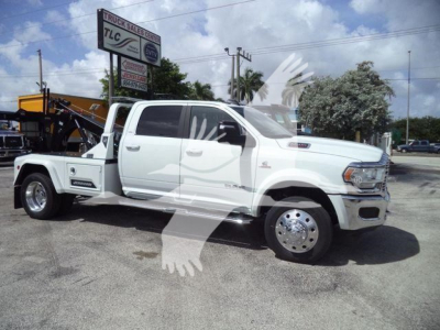 Ram 5500 tow truck with white cab and dual rear wheels, service bed. Visible text includes dealership signs and TLC Truck Sales Center in the background.