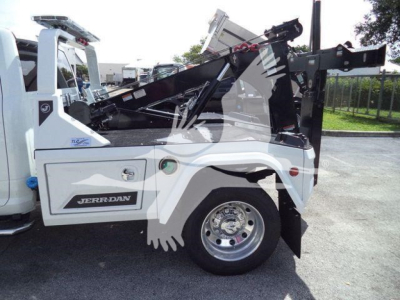 Ram 5500 tow truck side view showing heavy-duty winch bed and hydraulic hoist with 'Jerr-Dan' branding on the side. White cab and body with black chassis.