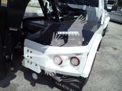 Ram 5500 Laramie winch truck rear view with white bumper and two circular taillights, black tonneau cover, and winch equipment visible in bed area.