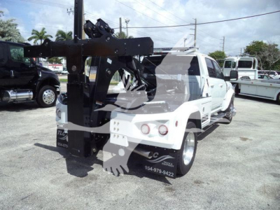 Tow truck with crane/winch mounting on back of white Ram 5500, winch apparatus visible, license plate area blocked by watermark, some text on side panels and bumper but not legible.