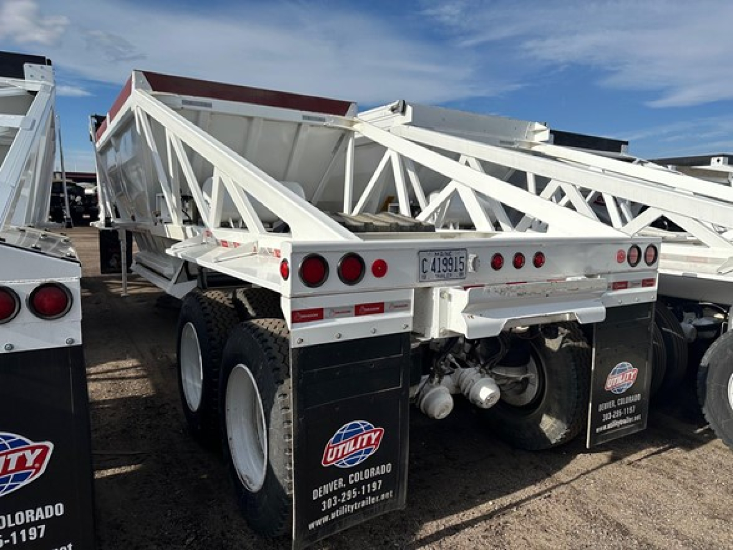 Dump trailer showing white LW21-40 Ranco dump trailer with dual rear axles and suspension, rear view including license plate and utility decals.