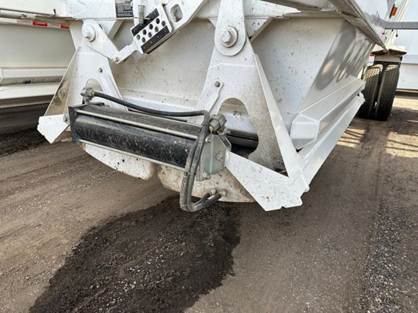 Ranco LW21-40 dump trailer hitch area showing hydraulic hoses and mounting bracket connected to a black hydraulic cylinder.