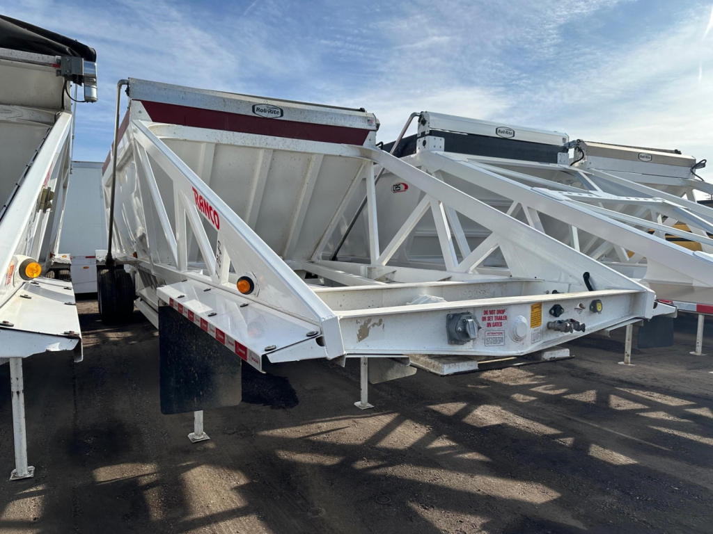 Ranco LW21-40 dump trailer in white, side view showing triangular frame and rear hitch, with other trailers in background.