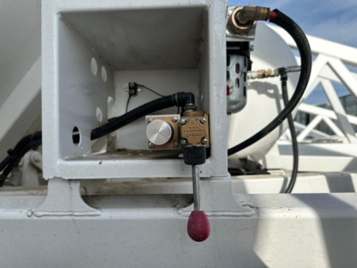 Dump trailer GD valve actuator and hydraulic lines inside a white square compartment with a small lever handle and electrical connector.