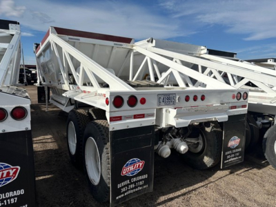 Dump trailer showing white LW21-40 Ranco dump trailer with dual rear axles and suspension, rear view including license plate and utility decals.