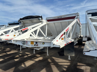White Ranco LW21-40 dump trailer showing rear and side frames with red RANCO logos, hydraulic hopper, and stake body. Visible stickers and warning labels on underside.