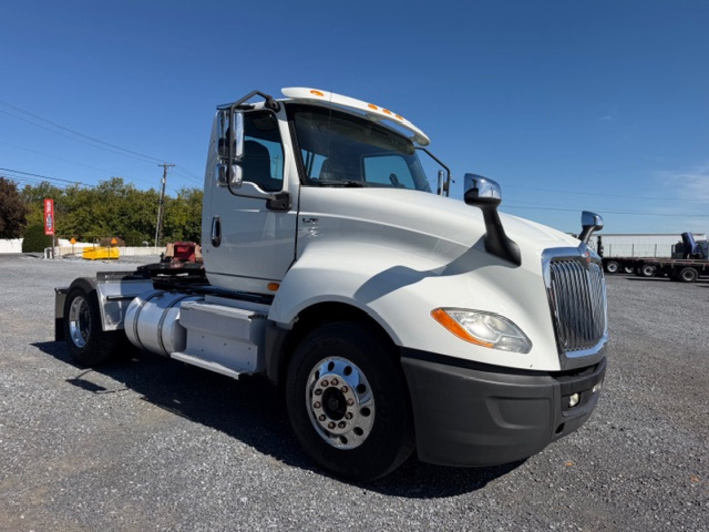 Truck cab side view of a white 2018 International LT625 conventional daycab showing front grille, dual fuel tanks, and wheel with hub.