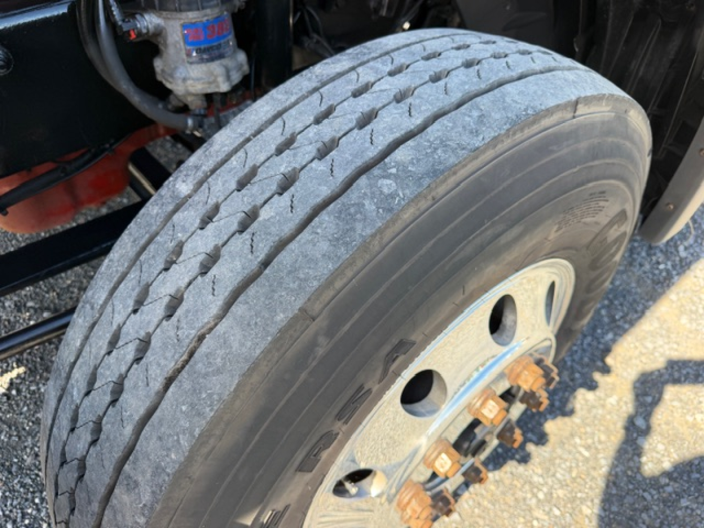 Truck wheel close-up showing front tire on International LT625 with visible tread wear and wheel hub bolts.