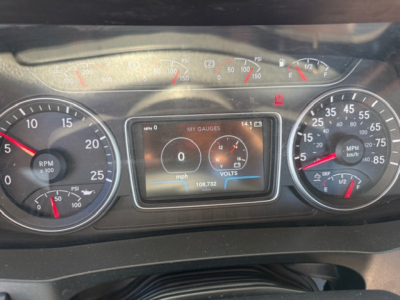 Dashboard view of a 2018 International LT625 showing the instrument cluster with RPM gauge, speedometer, and a central digital display reading 0 mph and 1413 miles? with gauge indicators.