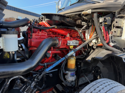 International LT625 engine bay showing a red engine with black air intake hose and yellow oil filter; various hoses and components visible.