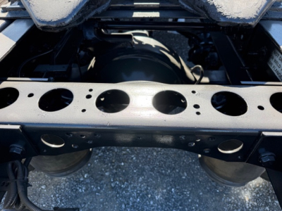 Truck rear chassis view showing frame rails and rear axle housing in a 2018 International LT625. Visible metal frame with circular holes and suspension components.