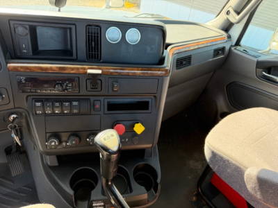 Truck interior: dashboard view of 2018 International LT625 with wood trim, analog gauges, transmission shifter, cup holders, and control panels visible.