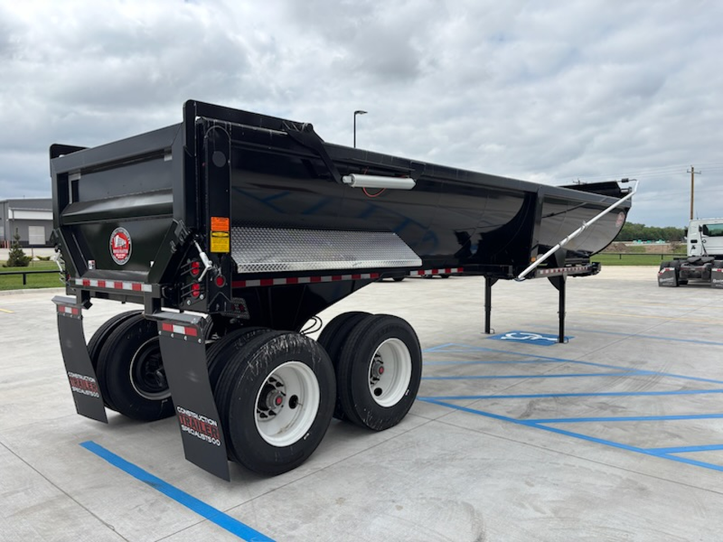 Dump trailer with dual rear axles and a hydraulic tailgate, black paint, reflective tape, and metal checker plate accents. Text visible: CTS HRD-32 branding on side.