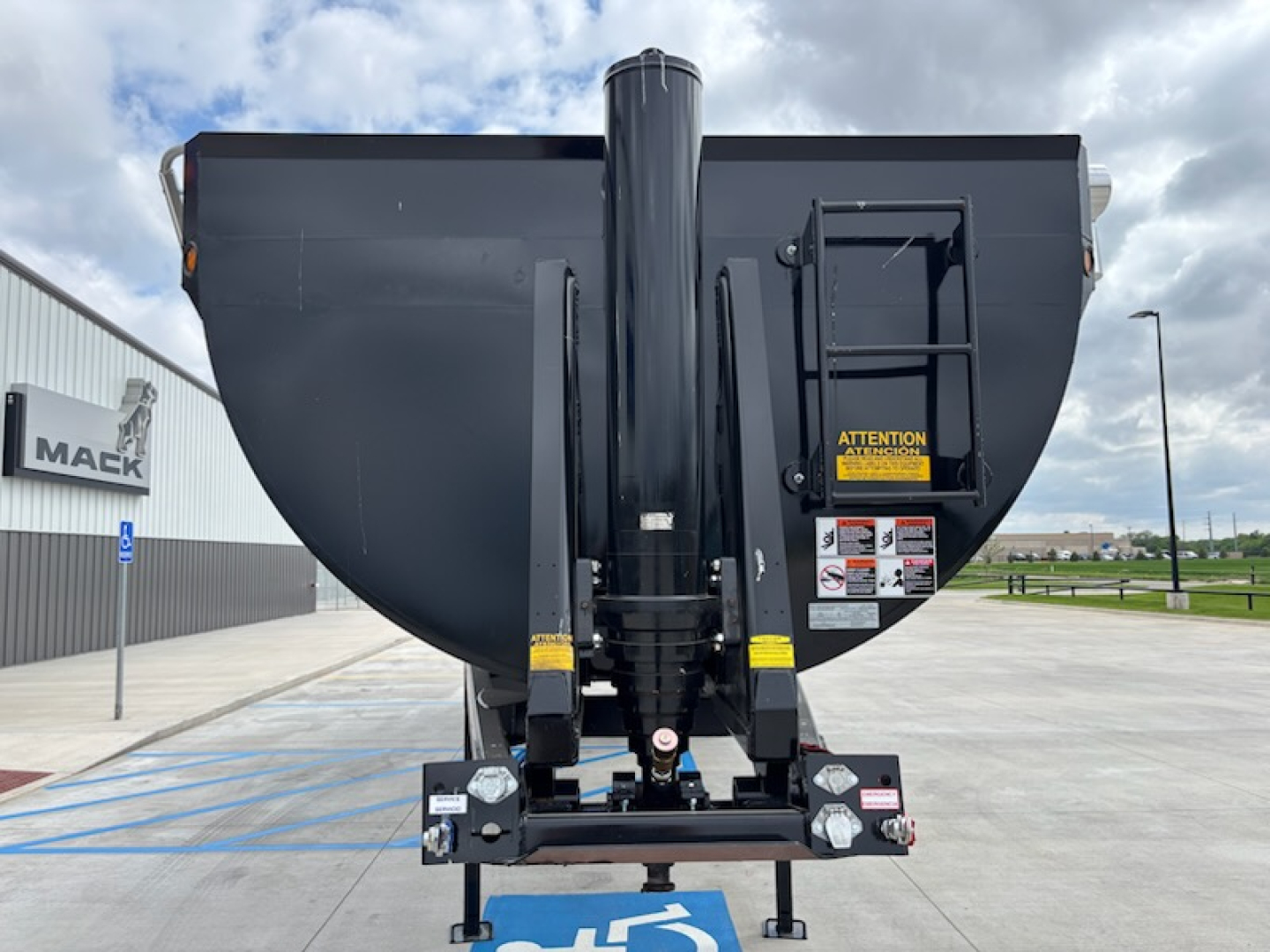Dump trailer hitch and front of CTS HRD-32 with vertical central support and hydraulic arms in view; warning labels visible on right side.