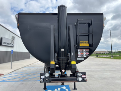 Dump trailer hitch and front of CTS HRD-32 with vertical central support and hydraulic arms in view; warning labels visible on right side.