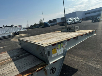 Trailer bed showing worn wood deck and metal frame of a 2019 Trail-Eze TE70 XTS trailer with warning stickers and hitch area visible.