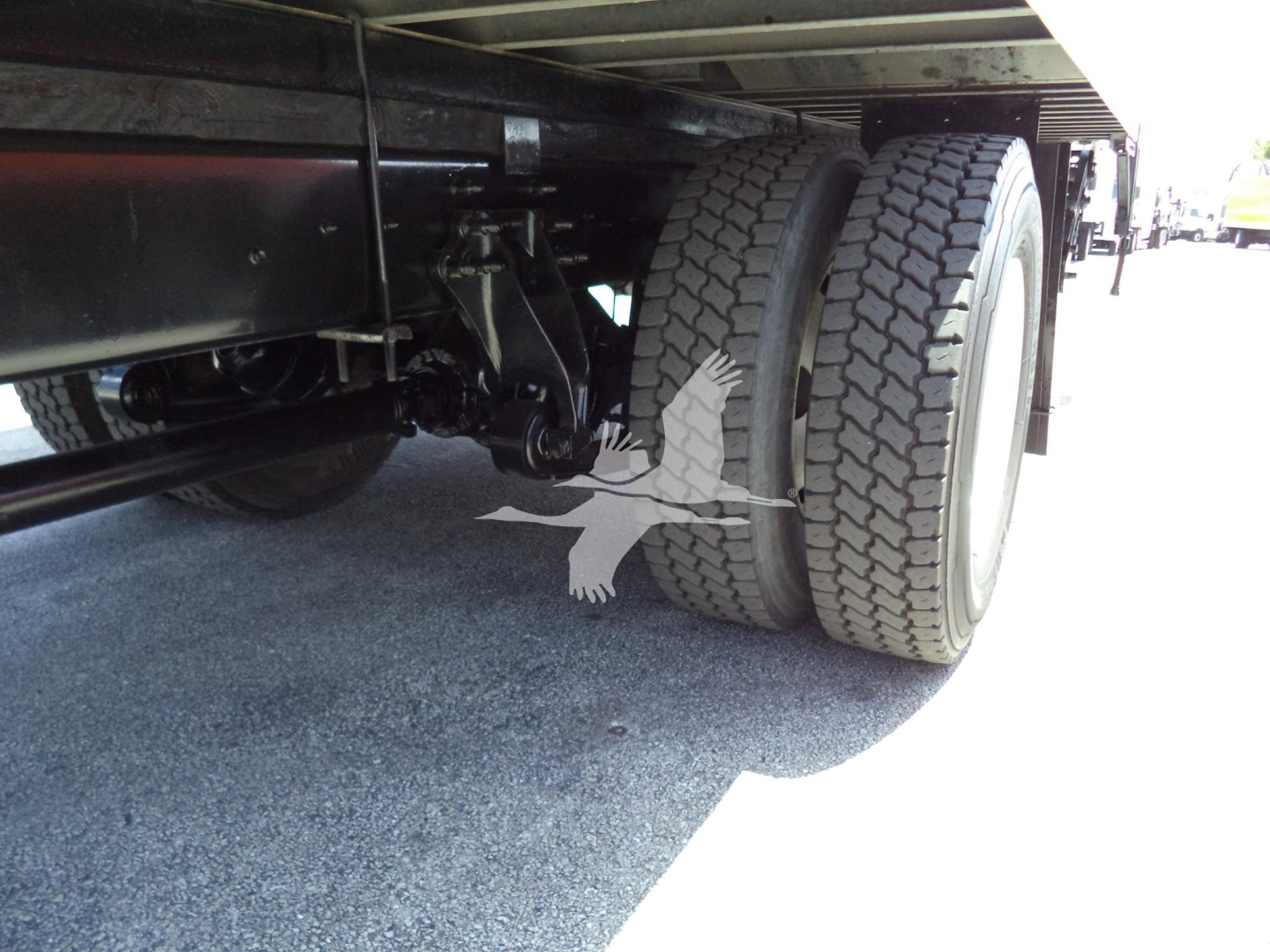 Truck undercarriage showing dual rear wheels and suspension components beneath a box truck.