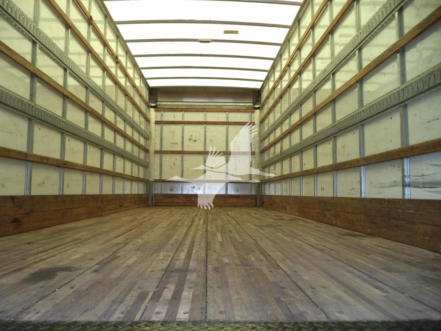 Truck cargo area showing empty box truck bed with wood floor and metal side walls.
