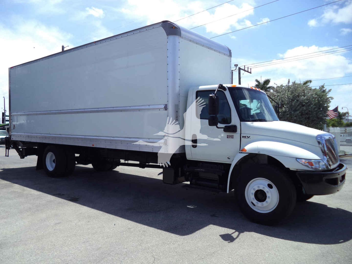 Box truck with white cab and large cargo box in profile view showing VIN and stock number information on listing.