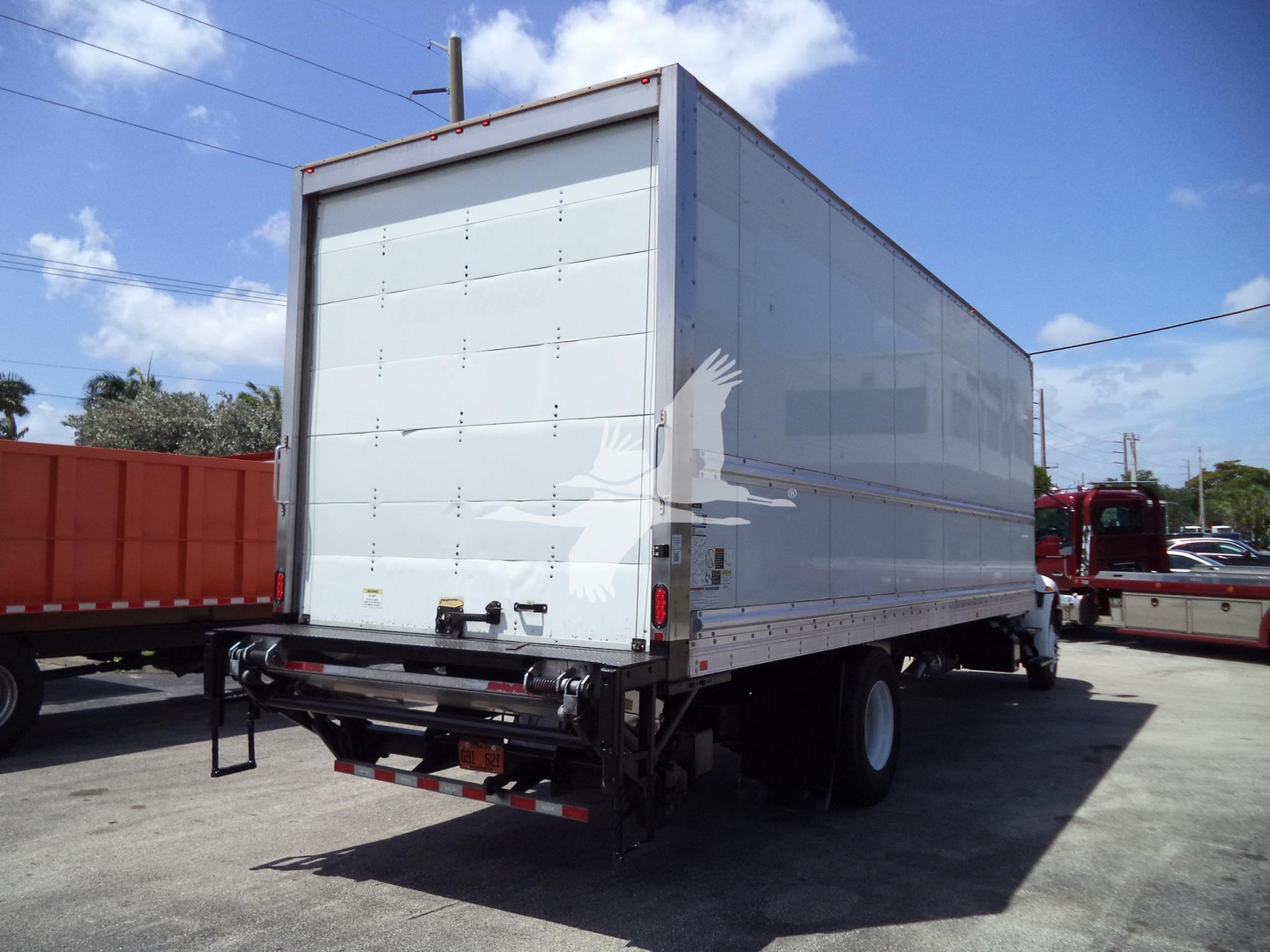 Box truck rear view showing back doors and taillights on a white cargo trailer attached to a truck.