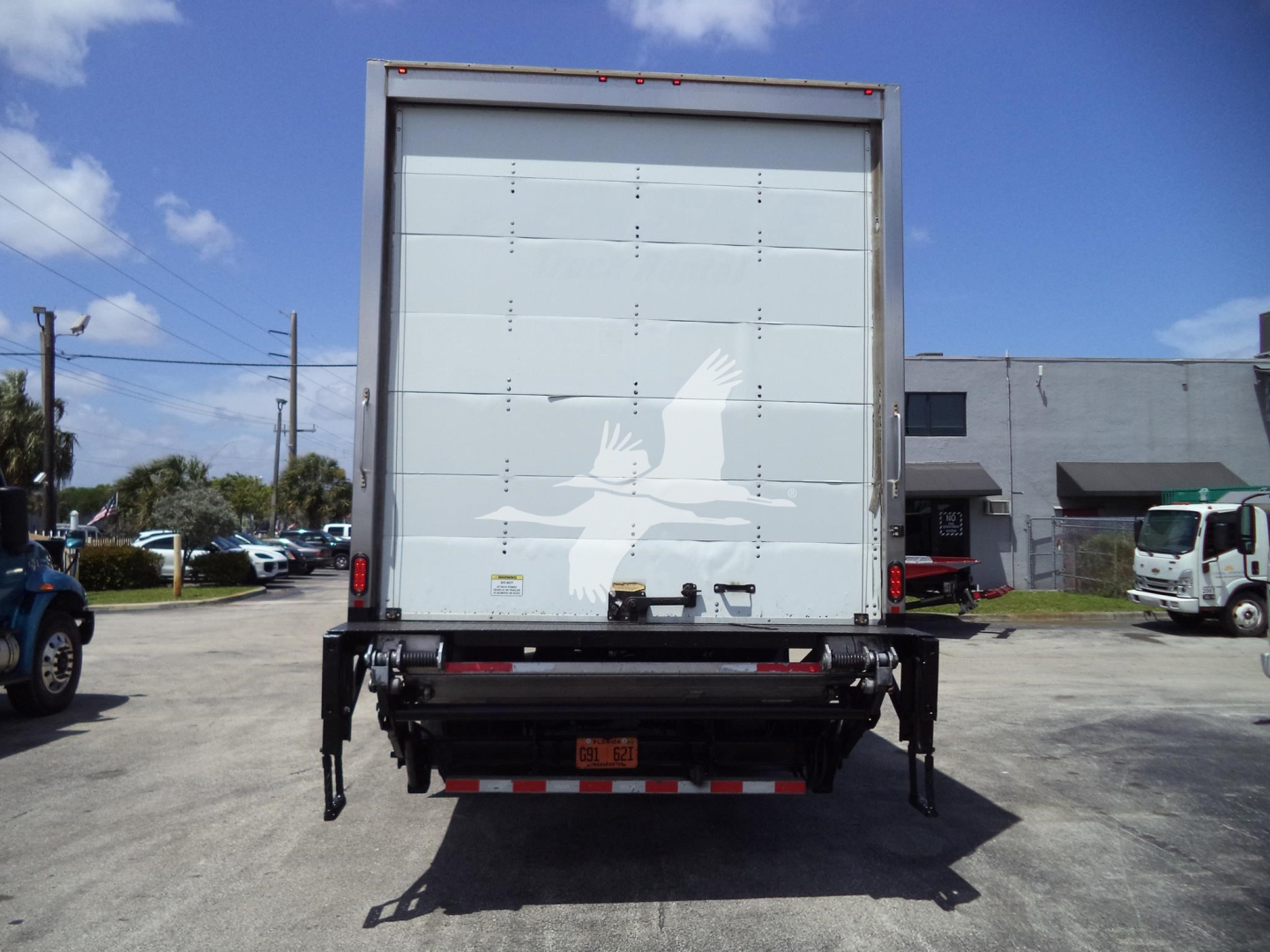 Back of a box truck showing a security decal and bumper with rear underride guard.