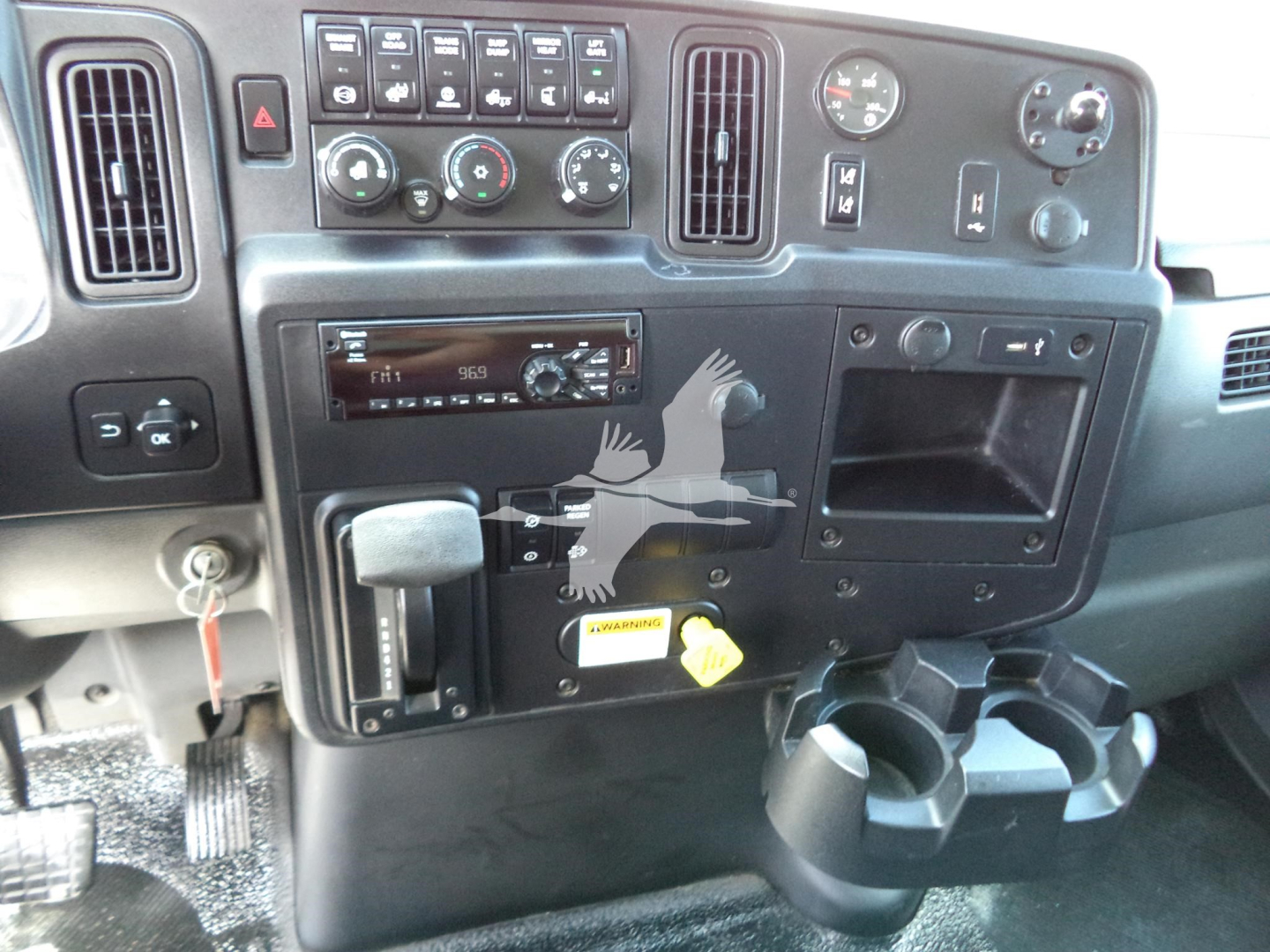 Dashboard of a 2021 International MV truck showing controls, vents, cup holders, and a keyring. Visible text includes on the center console radio display and various knobs.