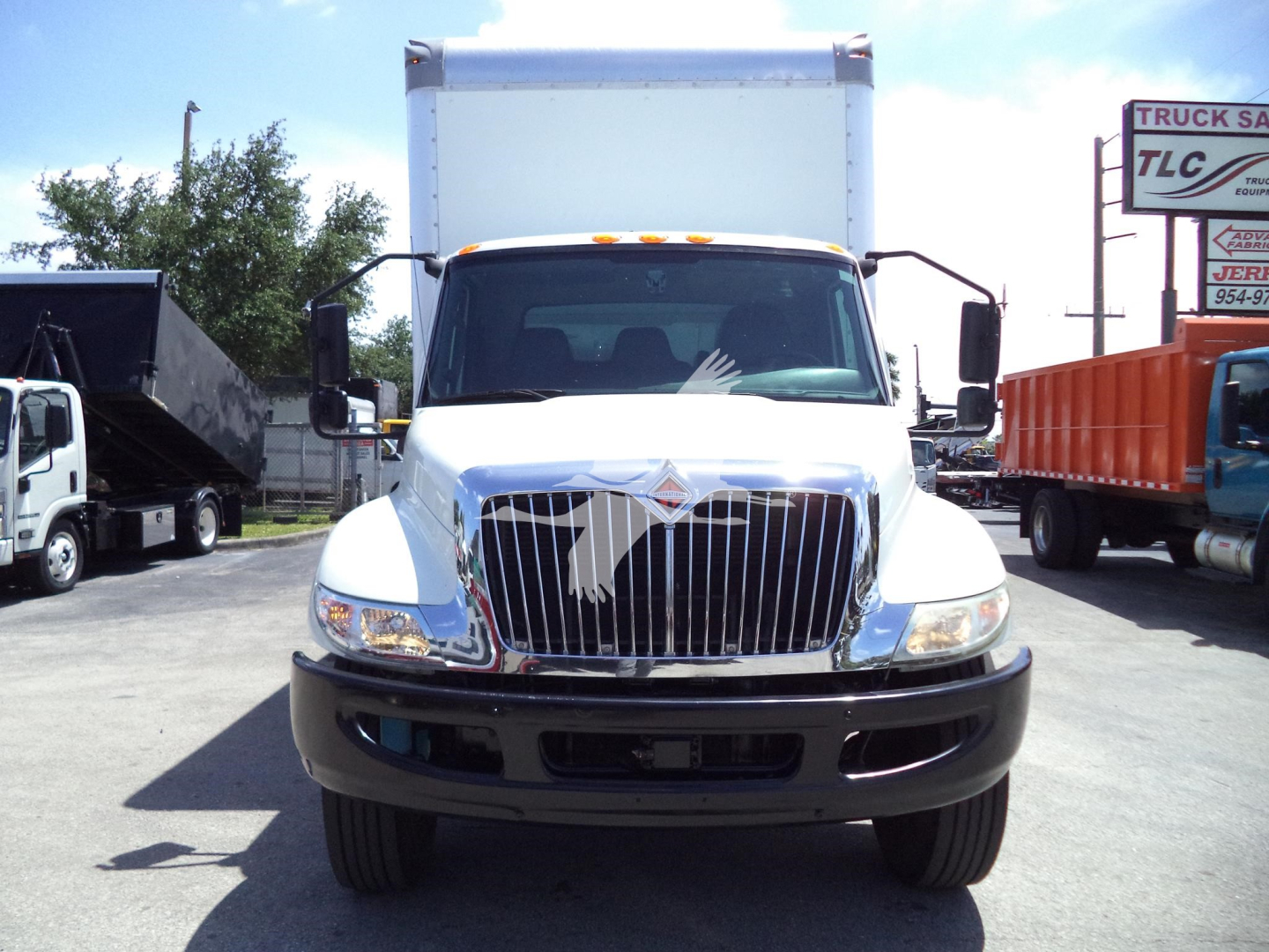 Truck front view of a white 2021 International MV with large chrome grille, headlights, and box truck body; no visible text on the truck itself.