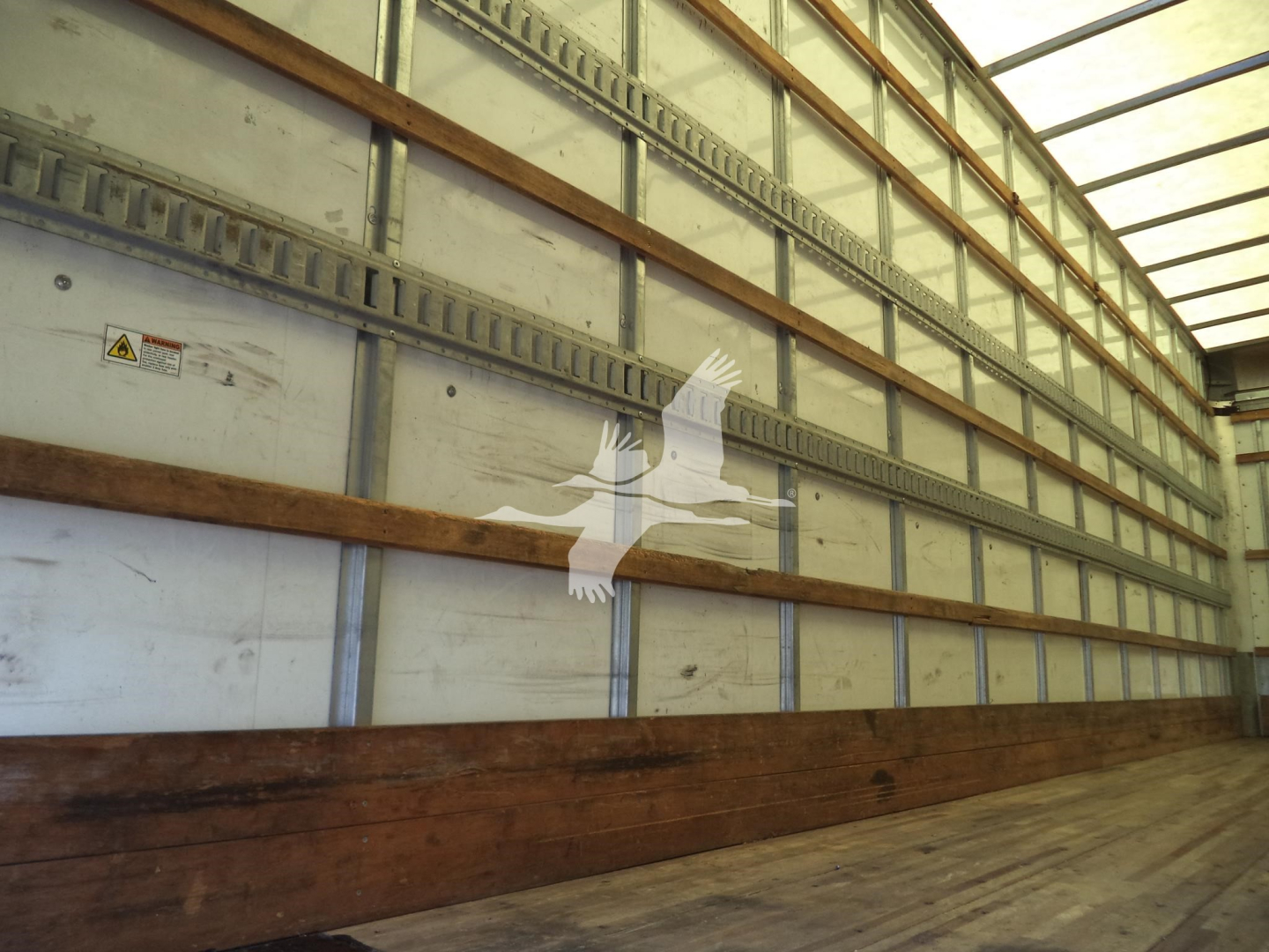 Image of a trailer interior with metal E-tracks and wooden floor planks inside a truck trailer.