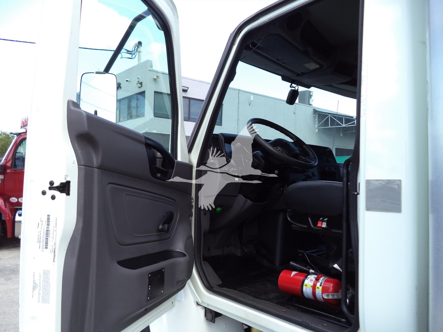 Truck cab interior showing open driver door and steering wheel view from outside.