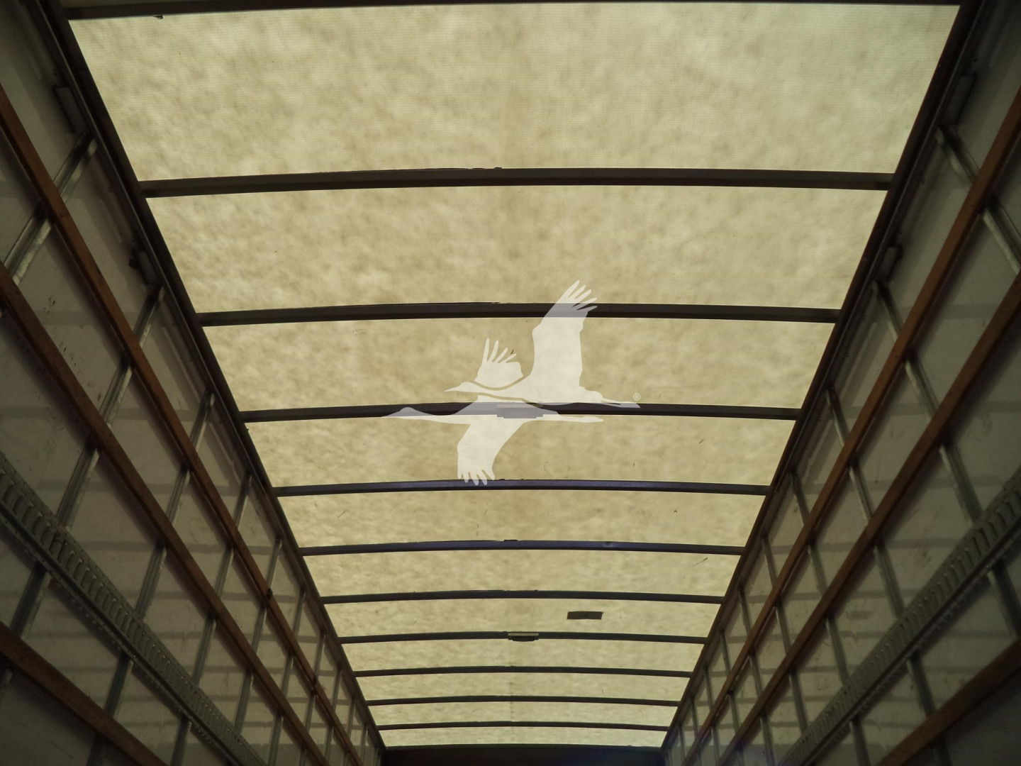Interior of a truck trailer with skylight panels and metal framing.