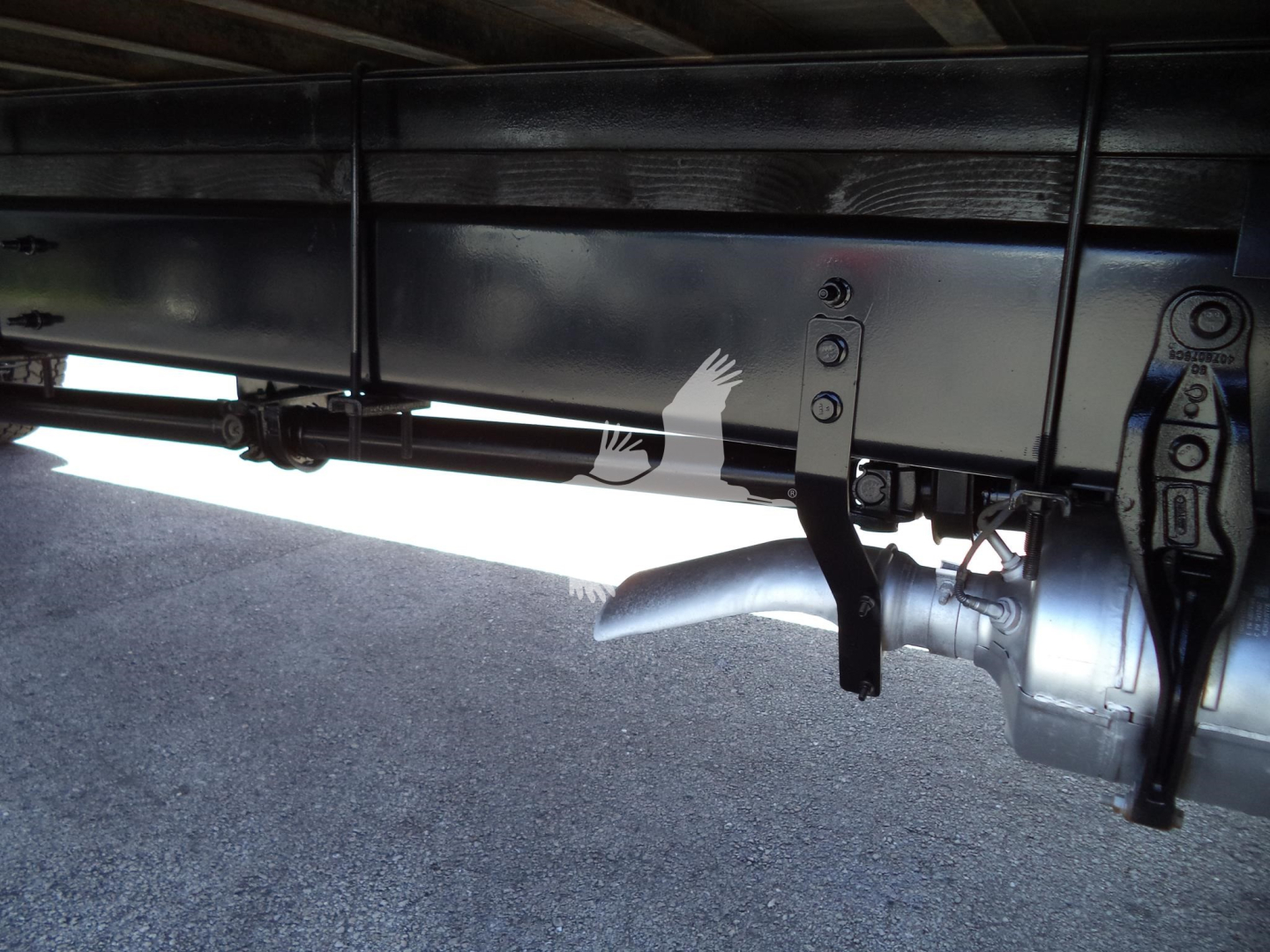 Underbody of a 2021 International MV box truck showing chassis frame, refuse of suspension, and fuel/air lines; visible hardware and a metallic connector at the rear.