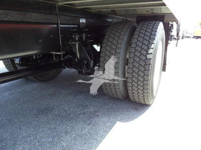 Truck undercarriage showing dual rear wheels and suspension components beneath a box truck.