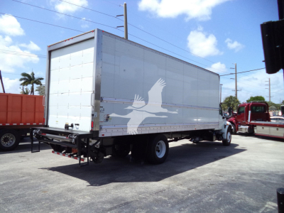 Truck trailer in a parking lot with box body and bird silhouette graphic on side, rear hitch visible.