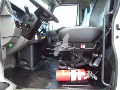 Cab interior of a 2021 International MV truck showing driver's seat, steering wheel, and a mounted fire extinguisher under the seat.