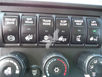 Trucks dashboard switches: exhaust brake, off road, trans mode, suspension dump, mirror heat, lift gate; control knobs below with climate/auxiliary icons.