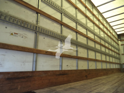 Image of a trailer interior with metal E-tracks and wooden floor planks inside a truck trailer.