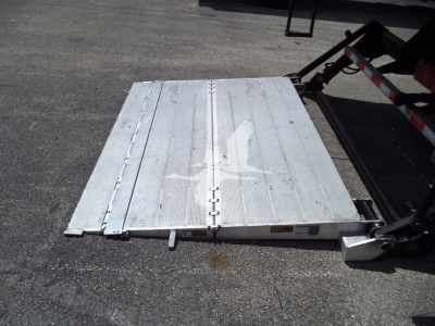 Rear view of a loading ramp on a 2021 International MV truck bed with aluminum platform and hinge mechanism.