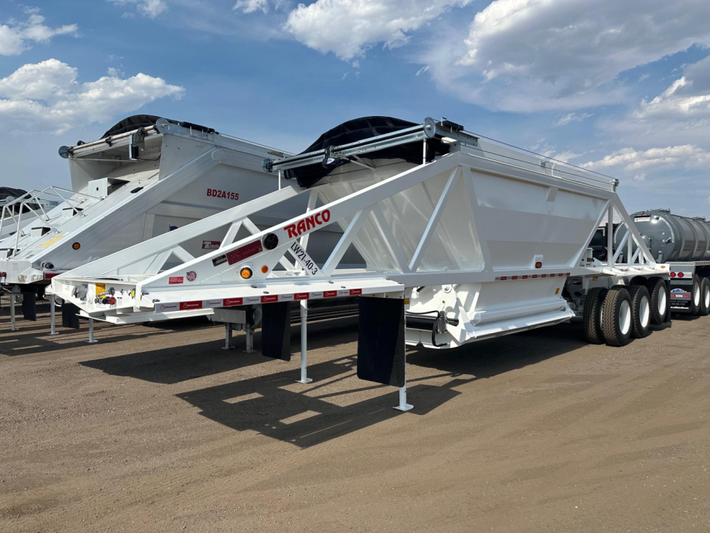 Ranco tri-axle bottom dump trailer with pintle hitch, rear lift, white chassis and black tarp roller, side view showing brand and dual-axle wheels.