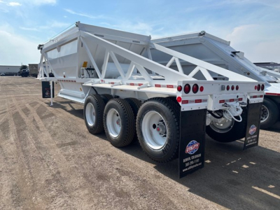 Tri-axle bottom dump trailer showing white steel frame, tandem axles, and rear emergency/setup components.