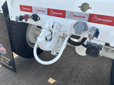 Bottom dump trailer hitch and connection points showing white painted hitch hardware and hydraulic hose fittings.
