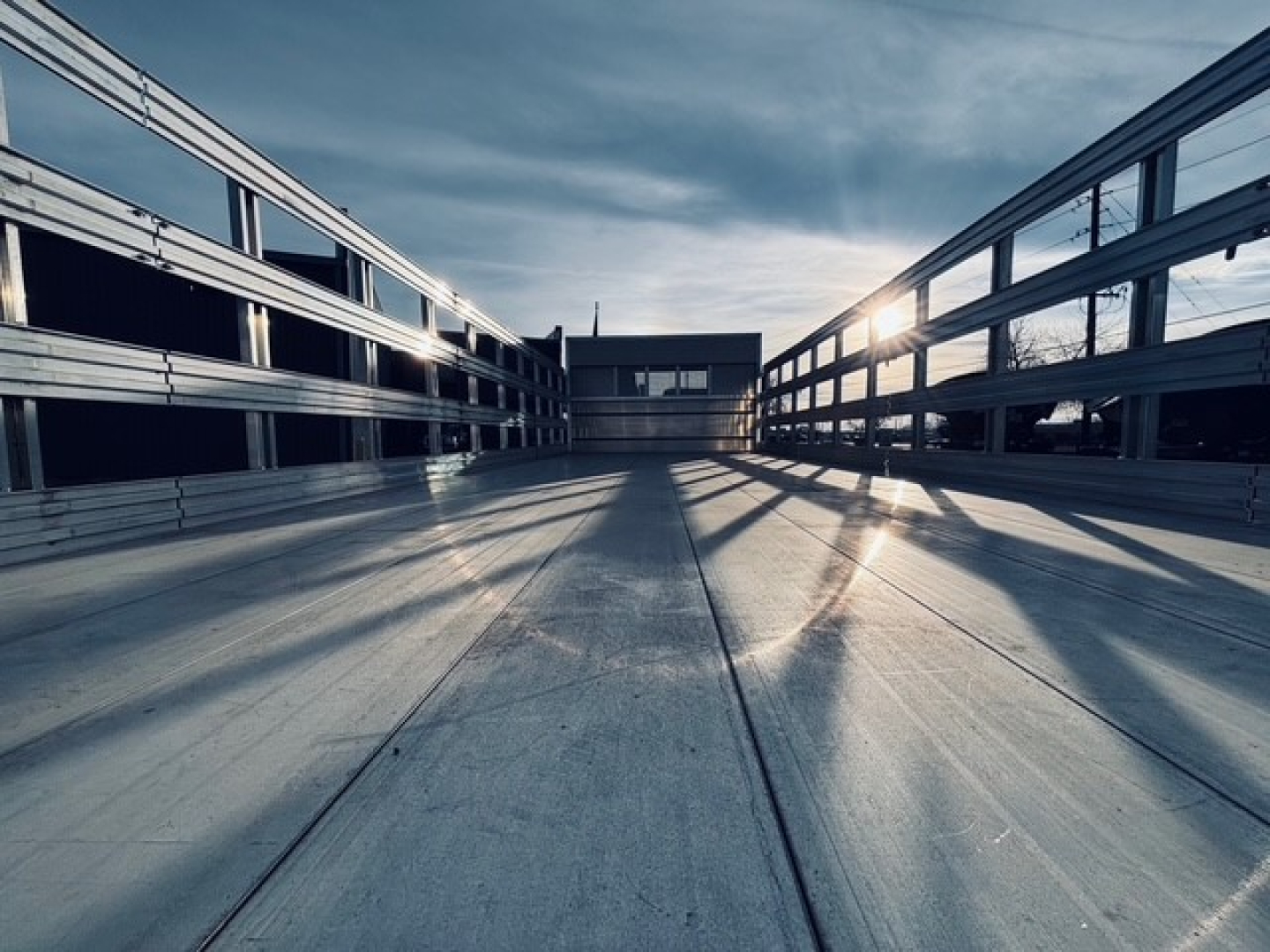 Flatbed truck bed showing metal side rails and open cargo area with bright light at end, 2025 Mack MD7 listing context not visible in image.