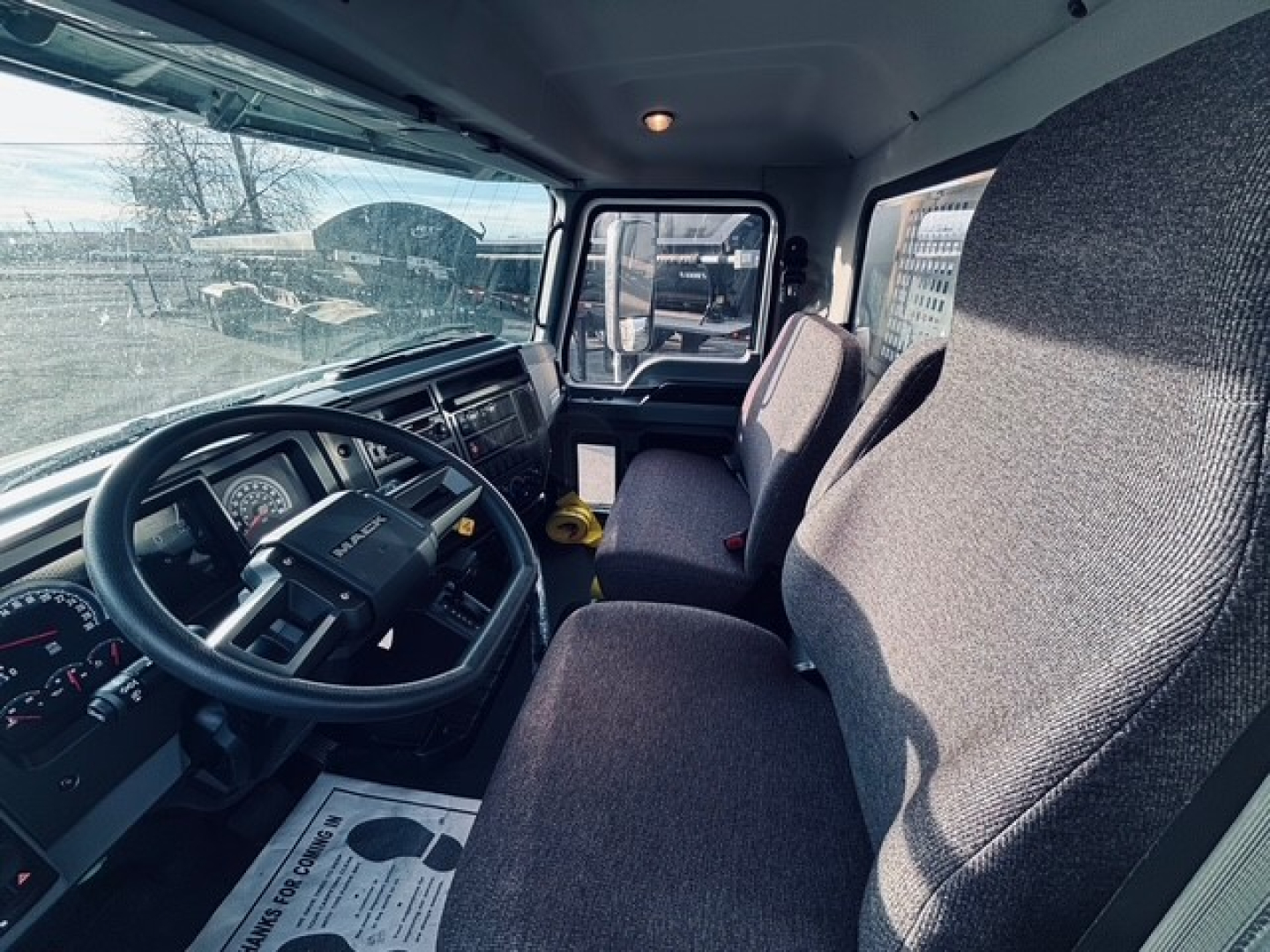 Mack MD7 cab interior showing steering wheel and front seats in view.