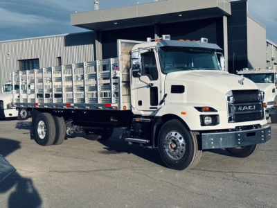 New 2025 Mack MD7 flatbed truck shown in a dealership lot with aluminum side rails and flatbed. Vehicle details visible on truck front grille and mirrors.