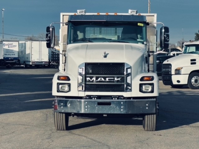 Front view of a white 2025 Mack MD7 flatbed truck showing grille with MACK lettering and bumper.