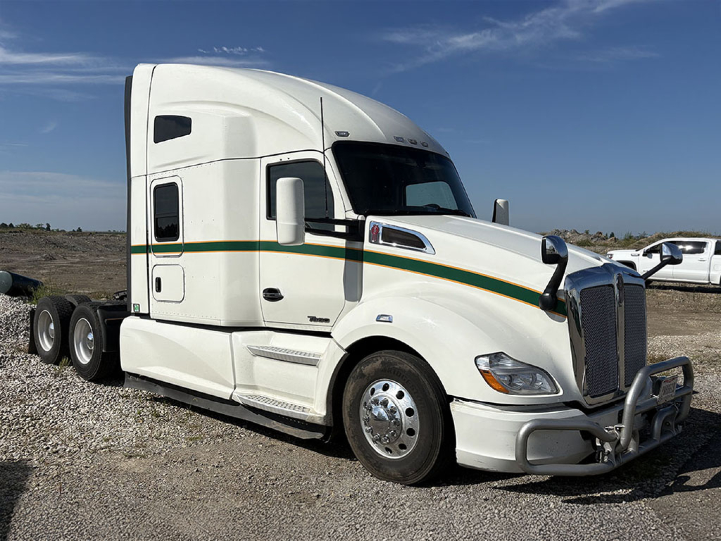 Kenworth T680 2019 conventional sleeper tractor, white with green and gold stripe, side view showing cab, front grille, and dual rear axles.