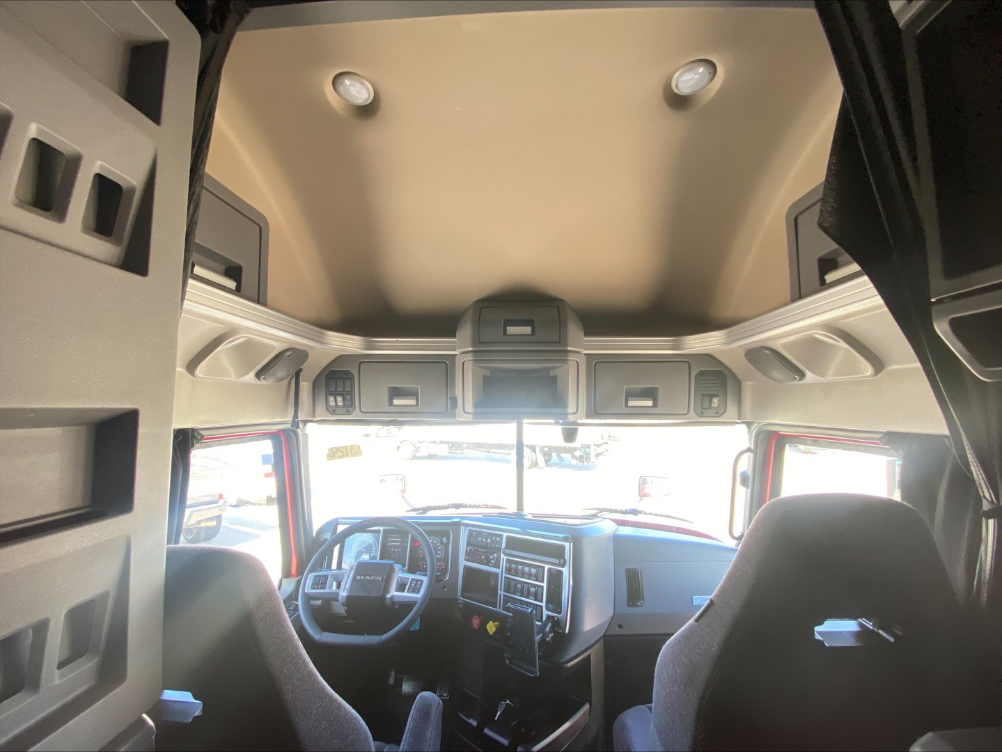 Truck cab interior showing steering wheel, dashboard, and bunk overhead storage with cabinets in a Mack AN64T70.