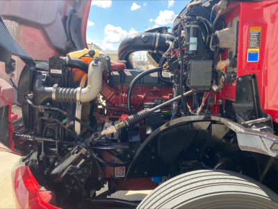 Mack AN64T70 engine bay showing air intake, hoses, wiring, and front wheel arch.