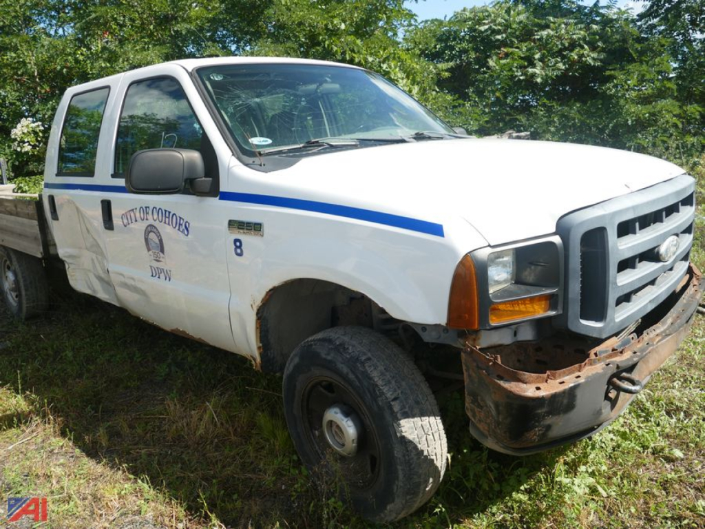 Ford F-250 Super Duty single rear wheel utility truck with damaged front bumper and city of boone DPW markings on white cab and flatbed, front right view.